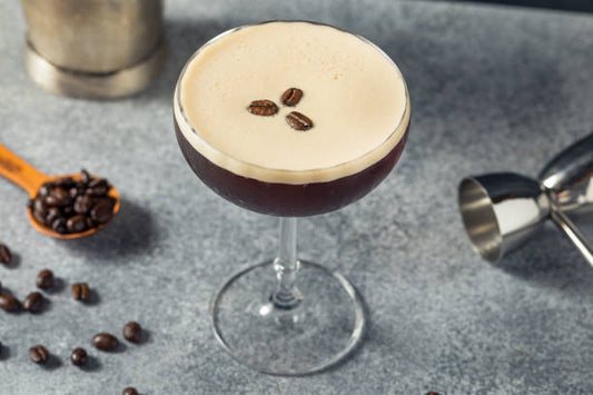 Martini glass with espresso cocktail in it. Coffee beans on the top of the drink. With a black shirt that says, Dead Men Tell No Tales. Cocktail Recipe